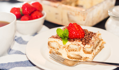 Homemade tiramisu cake decorated with strawberries Italian cuisine, Selective focus