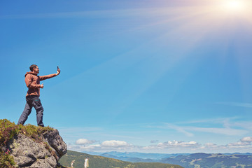 Obraz premium Tourist a taking selfie on peak above mountain valley with sunrise and fog