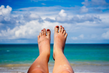 Naklejka premium feet with red nails on the background of Paradise beach and the ocean