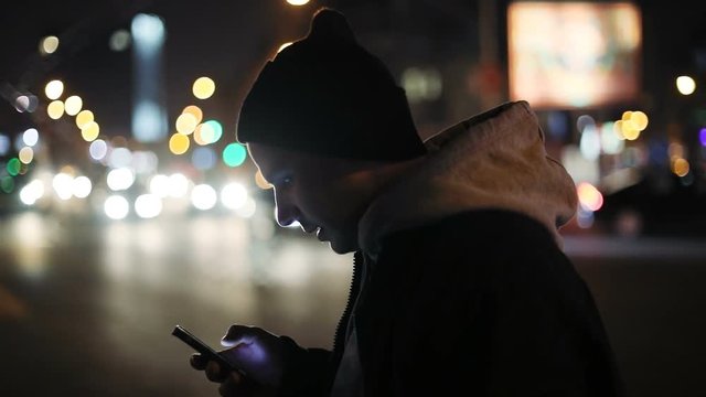 handsome man using modern digital device smartphone outside night cars traffic internet browser 3g social networking application touchscreen flipping pointing finger chat tech development pda gps 4K