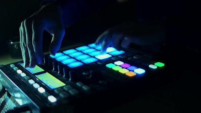 dj adjusting audio setting on the audio controller drum machine and playing music in the club