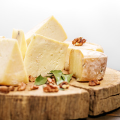An assortment of delicious nutritious cheeses on a wooden stand. The concept is healthy food, restaurant, cafe, vegetarianism.