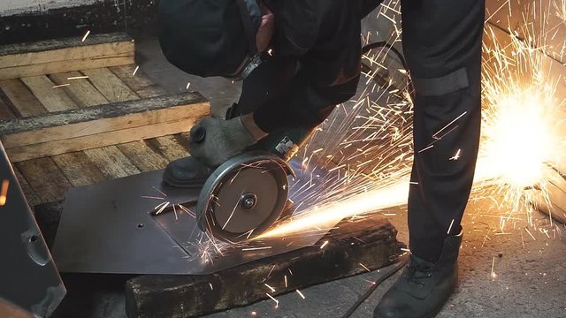 Worker cutting metal with many sharp sparks