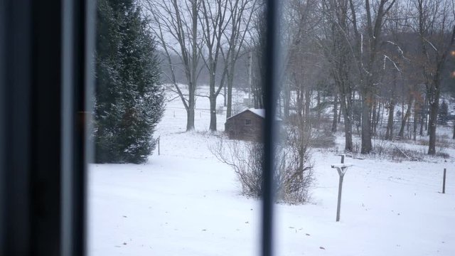 Looking out a glass window at snowy country landscape on Christmas morning in Pennsylvania