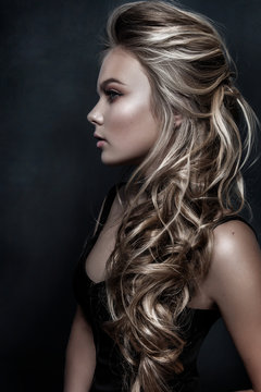 Beautiful girl with long wavy hair. fair-haired model with curly hairstyle and fashionable makeup