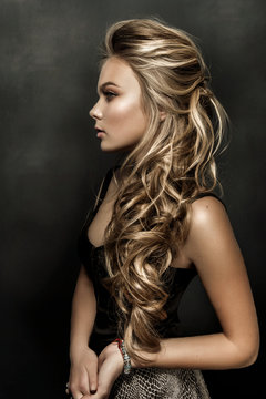 Beautiful girl with long wavy hair. fair-haired model with curly hairstyle and fashionable makeup