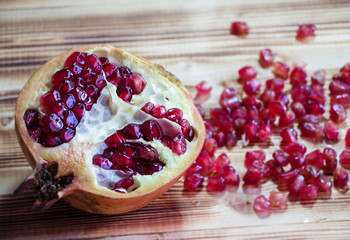 Closeup half of pomegranate put at the left side of wooden timber board,blurry light around.