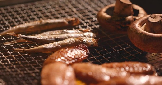 Barbecue with chicken wing, mushroom and capelin fish on grilled net