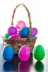 Decorated easter eggs are on a table and in a basket.