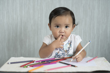 asian toddler / baby girl is having fun learning to use pencils. Education concept. human growth concept.