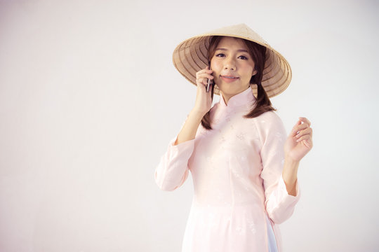 beautiful woman in pink dress and vietnam hat holding smartphone.