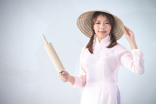 beautiful woman in pink dress and vietnam hat holding rolling pin.