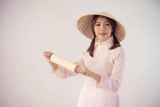 beautiful woman in pink dress and vietnam hat holding rolling pin.