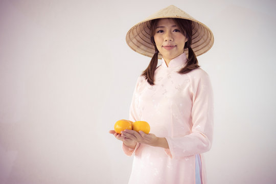 beautiful woman in pink dress and vietnam hat holding orange
