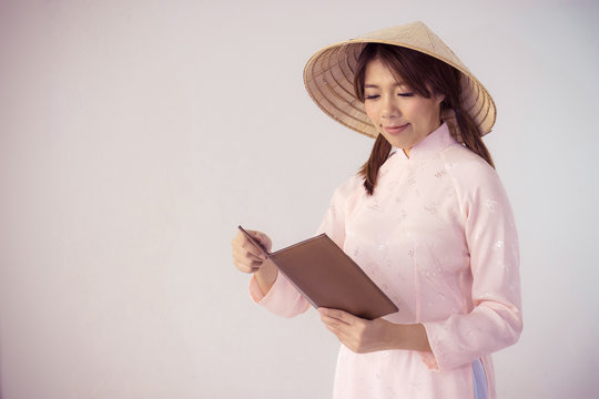 beautiful woman in pink dress and vietnam hat holding book