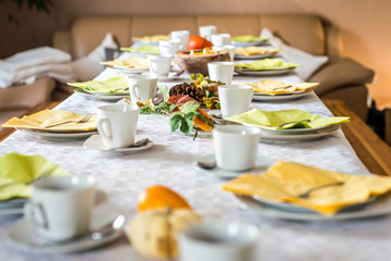 Beautiful festive dinner table colorful yellow fall helloween pumpkin decoration coffee mugs saucers plates and spoons