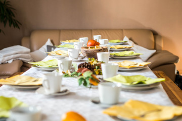 Beautiful festive dinner table colorful yellow fall helloween pumpkin decoration coffee mugs saucers plates and spoons