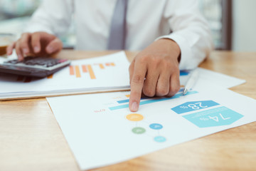 Businessman hand working with finances about cost and calculator and laptop with mobile phone on withe desk in modern office