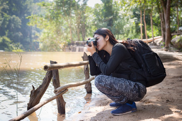 Asian woman backpack taking a photo with mirrorless camera
