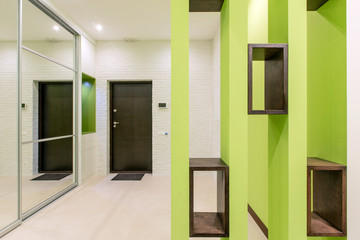 Design corridor in light green colors, which has a wardrobe with a mirror and shelves