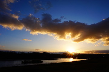 川の日没　青空　太陽の光芒