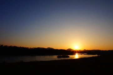 川の日没　青空　太陽の光芒