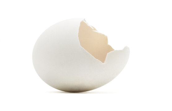 Empty golden cracked egg shell on white.
