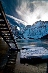 wooden ladder on mountain lake with blue sky and snowy mountains