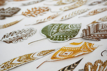 A lot of autumn dry leaves with white hand-drawn ethnic patterns. Selective focus.