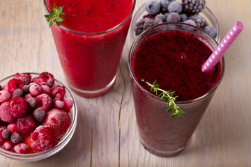 Frozen summer berries smoothie: blueberries, strawberries, raspberries, cranberries, currants and blackberries on wooden background, horizontal