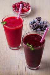 Frozen summer berries smoothie: blueberries, strawberries, raspberries, cranberries, currants and blackberries on wooden background, vertical