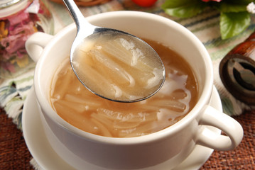 A close view of a soup spoon filled with onion soup