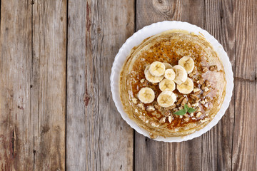 Pancakes with banana, walnuts and honey, and mint leaf, breakfast in rustic style, wooden background