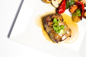 meat with grilled vegetables on a plate on white background