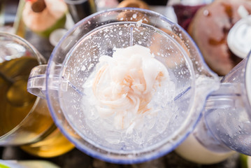 Flesh of coconut and ice in electric blender are doing make coconut juice smoothies.