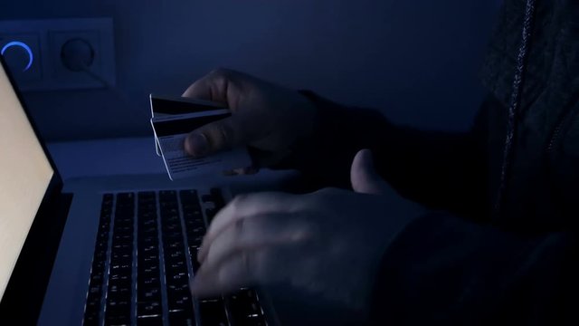 Closeup 4k footage of man working on laptop and holding credit cards