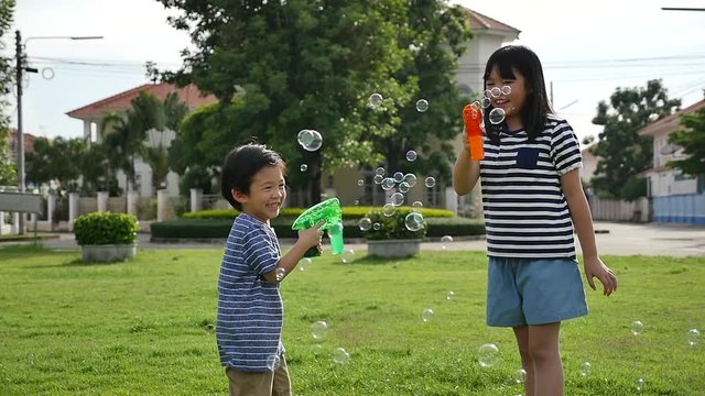 Cute Asian children Shooting Bubbles from Bubble Gun in the park slow motion 