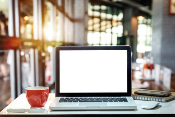 Front view of cup and laptop on table in office and background  in the coffee shop
