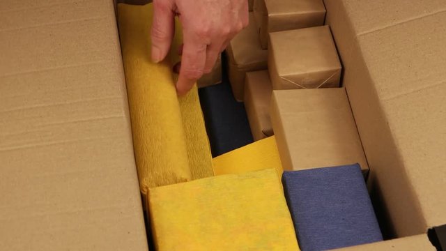 Person packs up the boxes with the gifts into the big  cardboard carton 