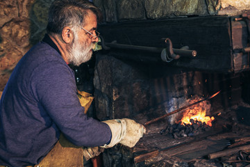 Senior blacksmith forge iron at work