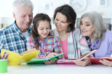 Grandparents with cute little girl doing homework