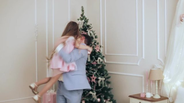 Child hugs his father near the Christmas tree