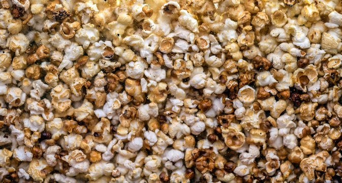 Hundreds popcorns background. Popcorns behind the glass of popcorn machine. Food background