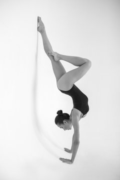 Young woman gymnast stands in a gymnastic position on a white background.