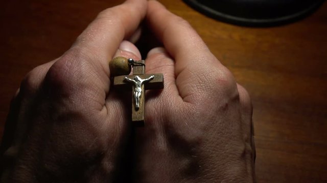 A wooden rosary in the hands of her husband during the prayer