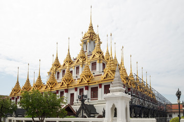 Fototapeta premium Golden Spires Against Cloudy Sky at Loha Prasart Buddhist temple complex