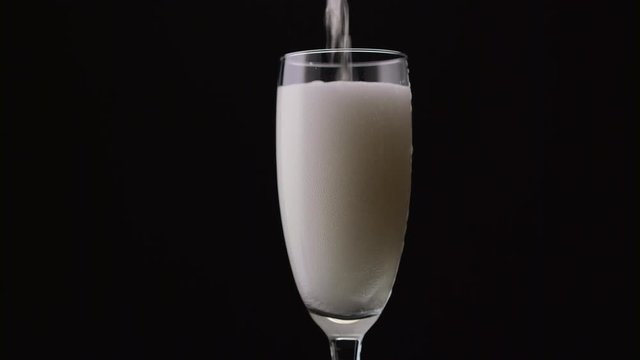 Waiter pours the champagne from the bottle into the glass. Black background