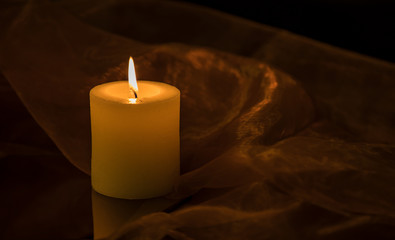 Simple candlelight on a table surrounded by a fine cloth.