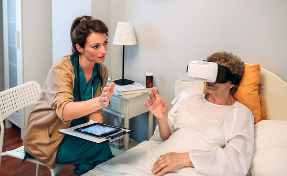 Older patient using virtual reality glasses to see her spine while female doctor explains