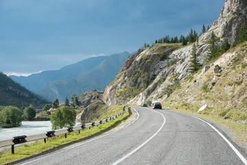 Naklejka premium Asphalt winding road in the mountainous area in the summer and sky with clouds